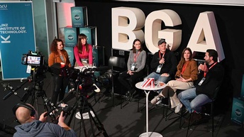 Interview vor einer Kamera mit sechs Menschen. Dahinter groß der Schriftzug BGA
