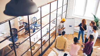 Junges Team beim Brainstorming vor einem Whiteboard in einem offenen Büro