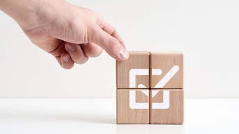 Vier aufeinander gestapelte Holzwürfel mit dem Aufdruck für Checkbox 