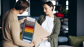 Ein Paar sucht einen passenden Stoff für Kissen und eine Sitzgarnitur