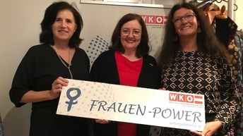 Drei Frauen halten ein Schild mit dem Text: Frauen-Power