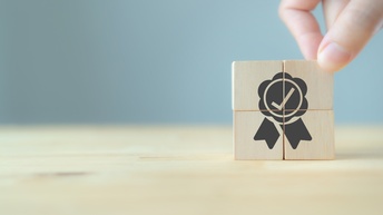 Eine Hand stapelt vier Holzwürfel aufeinander, die dein Symbol für Garantie ergeben