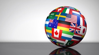 Nahaufnahme einer Weltkugel, die auf einem schwarzen Tisch liegt. Auf der runden Kugel sind Flaggen als Rechtecke abgebildet. Die Weltkugel wirft einen Schatten auf dem Tisch, der Hintergrund ist weiß. 