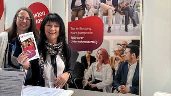 Zwei Personen bei einem Messestand