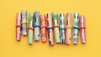 Verschiedene Euroscheine in Rollen mit Gummibändern auf gelbem Hintergrund