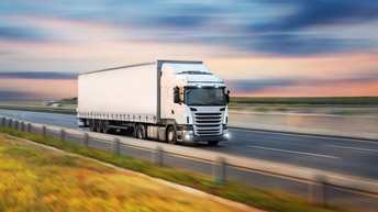 Weißer LKW beim Fahren in ländlichem Gebiet, umgebende Landschaft bewegungsunscharf