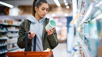 Young women reads product label while buying diary product