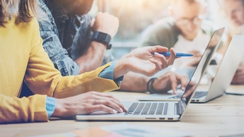 Mitarbeiter:innen arbeiten an den Laptops