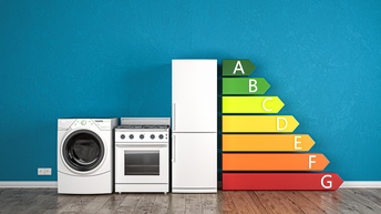 Abbildung von Elektronikgeräten mit der Anzeige der Energieeffizienzklassen vor einer blauen Wand
