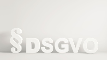 Weißer Schriftzug DSGVO mit Paragraphenzeichen vor einer weißen Wand