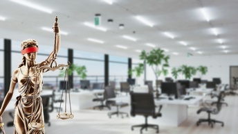 Justitia im Fokus vor Bürokulisse