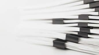 Nahaufnahme mehrerer Stapel Papiere vor weißem Hintergrund