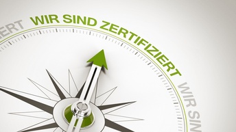 Nahaufnahme einer Kompass-Darstellung, bei welcher die Kompassnadel auf den Schriftzug 