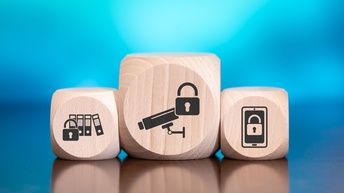 Drei Holzwürfel mit Aufdruck schwarzer Icons zum Thema Datenschutz, private Daten vor einem blauen Hintergrund