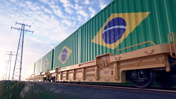 Seitliche Aufnahme eines Zuges auf Gleisen mit mehreren Waggons, auf denen jeweils die brasilianische Flagge ist