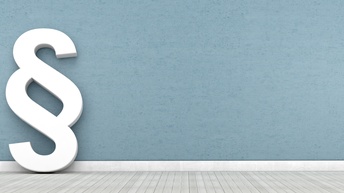 3D-Rendering eines weißen Paragrafenzeichen, das an einer blauen Wand lehnt