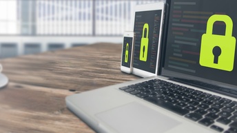 Laptop, Tablet und Smartphone stehen geöffnet mit Schlosssymbol aneinandergereiht auf einem Tisch