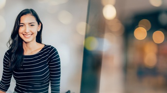 Porträt einer lächelnden Person in weißschwarz gestreiftem Oberteil, Hintergrund verschwommen mit Lichtflares