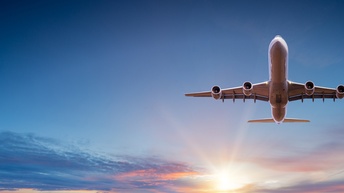Ansicht Unterboden eines Flugzeugs in der Luft, im Hintergrund Sonne, Wolken und blauer Himmel