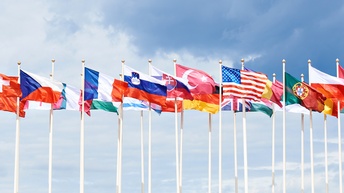 Mehrere Länderflaggen im Wind wehend, im Hintergrund Himmel mit Wolken