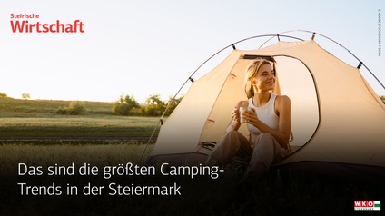 Eine blonde Frau sitzt auf einer Wiese vor einem beigen Zelt