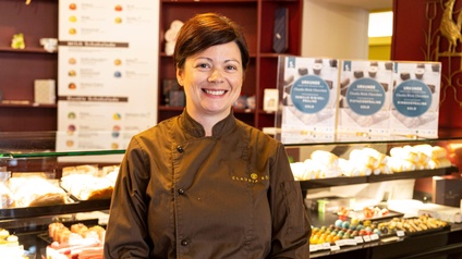 Eine lachende Frau vor einer Vitrine mit Konditorware.