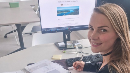 Eine lächelnde Frau vor einem Computerbildschirm.