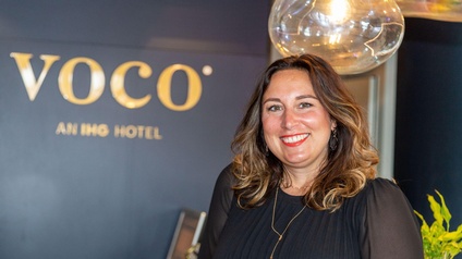 Eine lächelnde Frau vor einem Firmenlogo.