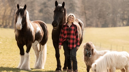 Eine Frau zwischen Pferden und Ponys.