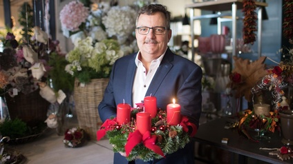 Innungsmeister Kurt Glantschnig hält einen Adventkranz mit roten Kerzen