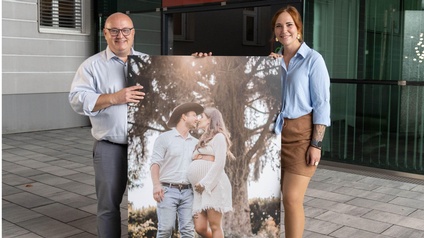 Michael Linzer und Elisa Zarfl halten ein großflächiges Foto am Vorplatz der Wirtschaftskammer Kärnten