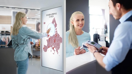 Fotomontage zweier Bilder: Eine Person berührt großen Touchscreen mit Schriftzug international stores und lächelnde Person hält Kreditkarte in Händen, andere Person unscharf im Vordergrund Zahlungsgerät