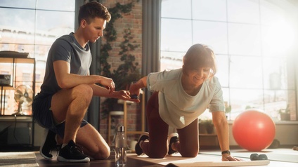 Eine Frau mit einem Personal Trainer beim ausführen von Sportübungen