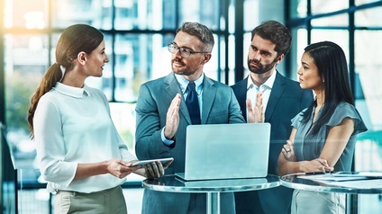 Vier Personen stehen um einen Stehtisch und unterhalten sich