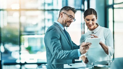 Zwei Personen stehen nebeneinander und schauen auf ein Tablet