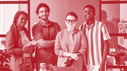 Junges Kreativ-Designteam bestehend aus zwei Frauen und zwei Männern posiert vor einem Laptop