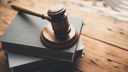 Richterhammer liegt auf mehreren Büchern auf hölzernen Untergrund