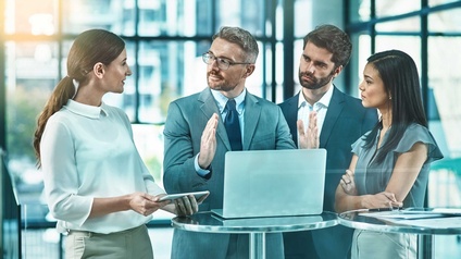 Vier Personen stehen um einen Stehtisch und unterhalten sich