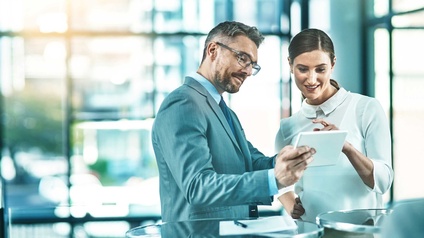 Zwei Personen stehen nebeneinander und schauen auf ein Tablet