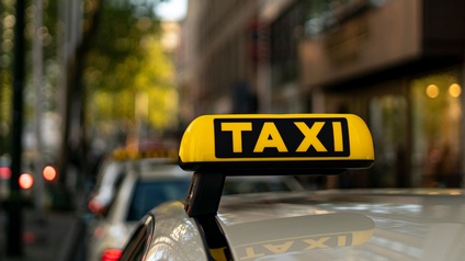 Gelbes Taxischild vor unscharfem begrüntem Hintergrund