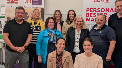 Gruppenfoto von Männern und Frauen - im Hintergrund sieht man Roll-ups
