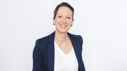 Portät von einer Frau mit kurzen Haaren, dunkelblauem Sakko und weißem Shirt vor weißem Hintergrund