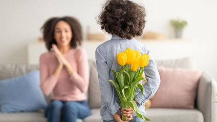 Kind überreicht Frau/Mutter Blumen