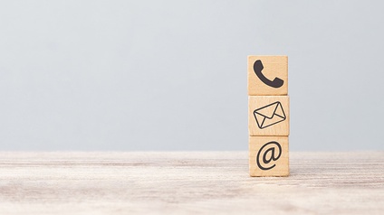 Drei Holzwürfel aufeinander gestapelt mit Kontaktsymbolen Telefonhörer, Briefumschlag und @