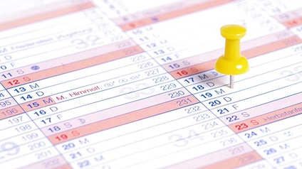 Detailansicht gelber Pinnadel in Kalender steckend