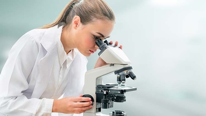 Person blickt durch Mikroskop