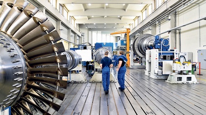 Zwei Personen in einer Industrie-Halle mit großer Maschine