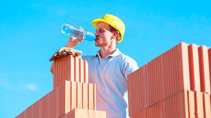 Bauarbeiter trinkt aus einer Flasche Wasser