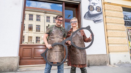 Harry und Lissi Steinhöfer mit einer Riesenbrille vor ihrem Optikergeschäft in Graz.