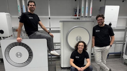 Nahaufnahme von drei Personen und Wärmepumpen. Eine Person sitzt auf einer Wärmepumpe, eine sitzt vor einer Pumpe und eine lehnt daneben